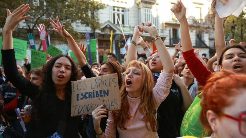 Uma manifestante segura um cartaz onde se lê “Os lápis escrevem todos os dias”, enquanto trabalhadores e estudantes argentinos participam de uma marcha para protestar contra o corte de verbas das universidades públicas, em Buenos Aires, Argentina, em 12 de maio de 2026