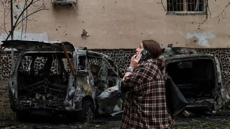 Morador de Odessa fala ao telefone em meio a carros destruídos por ataque russo