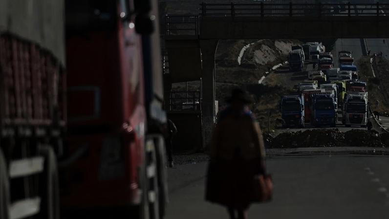 A woman walks among trucks stranded for days as protesters block a major highway, demanding the resignation of President Rodrigo Paz amid an ongoing economic and fuel crisis, in Apacheta, Bolivia, May 13, 2026. REUTERS/ Claudia Morales