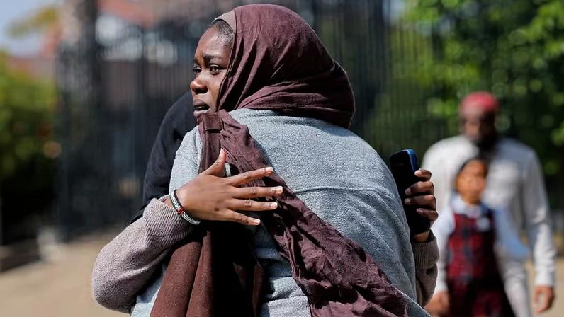 Mulheres se abraçam enquanto esperam as crianças saírem da mesquita , em uma área de concentração, no local do tiroteio no Centro Islâmico em San Diego , Califórnia, EUA, em 18 de maio de 2026