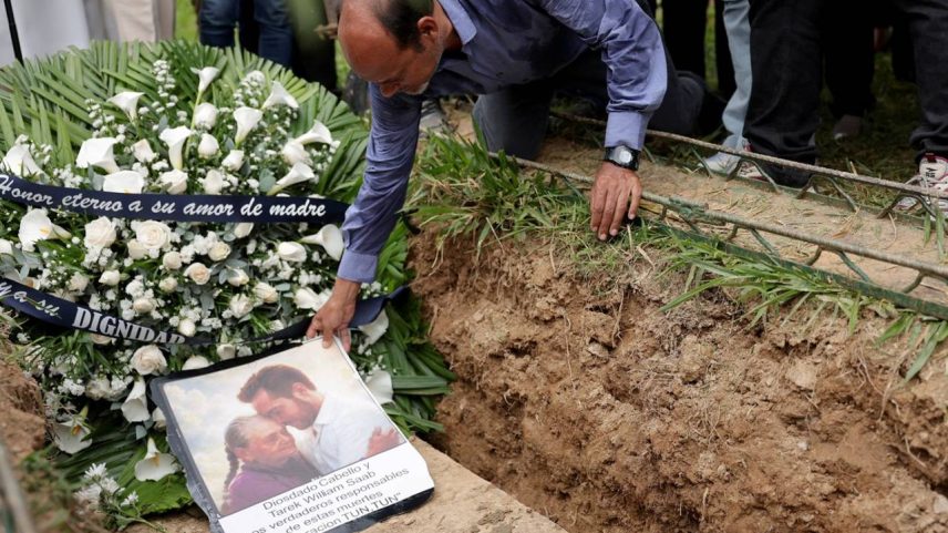 Gabriel Quero posiciona um retrato gerado por IA de sua mãe, Carmen Navas, e de seu irmão, Víctor Quero, durante o funeral de Carmen, que morreu pouco depois de as autoridades confirmarem que Víctor havia morrido sob custódia do Estado, após quase um ano em que ela passou procurando por ele, em Caracas, Venezuela, 19 de maio de 2026. REUTERS/Gaby Oraa TPX IMAGES OF THE DAY