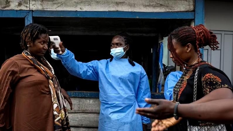 Uma profissional de saúde mede a temperatura de uma mulher que passa pelo posto de controle de Kanyaruchinya, enquanto autoridades e agências humanitárias intensificam os esforços para conter um novo surto de Ebola envolvendo a cepa Bundibugyo, na entrada norte da cidade de Goma, província de Kivu do Norte, República Democrática do Congo , em 20 de maio de 2026 — Foto: REUTERS/Arlette Bashizi
