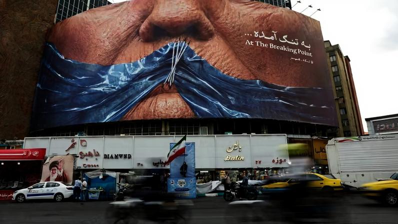 Pessoas passam de carro por um outdoor anti-EUA que retrata o presidente dos EUA, Donald Trump, e o Estreito de Ormuz, em Teerã, Irã , 17 de maio de 2026