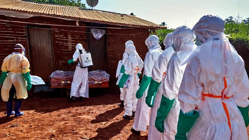 Trabalhadores da Cruz Vermelha, usando equipamentos de proteção individual (EPI), desinfetam a casa de pessoa que morreu de ebola, na província de Ituri, República Democrática do Congo — Foto: REUTERS/Gradel Muyisa Mumbere