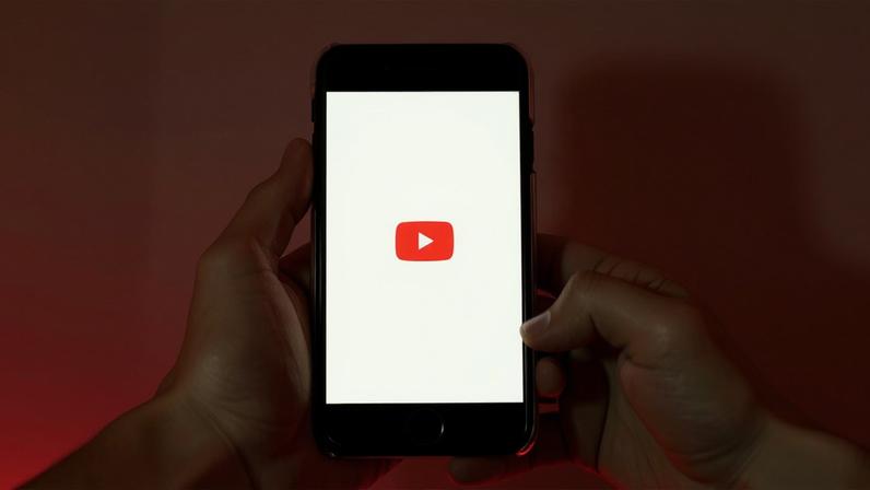A imagem contém a logo da plataforma Youtube em um celular.