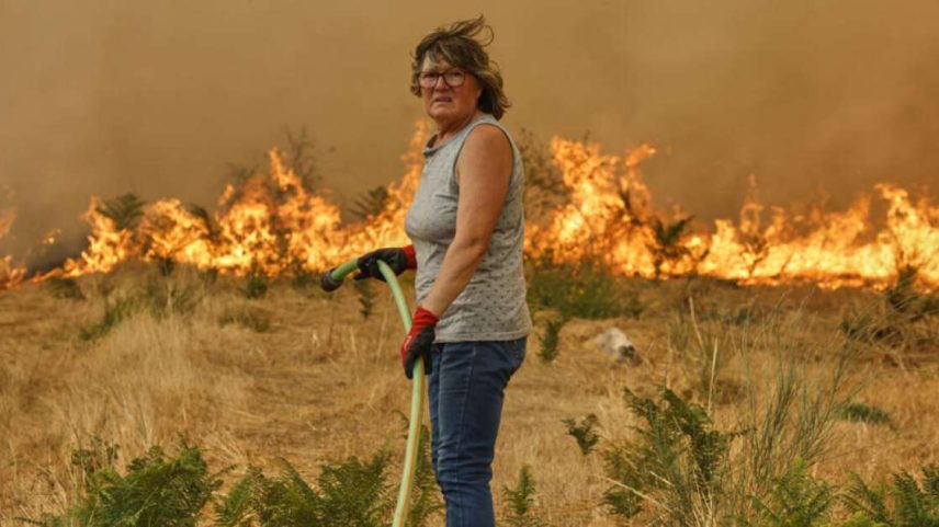 Uma mulher tenta apagar um incêndio em Santa Baia de Montes, no noroeste da Espanha, em 14 de agosto de 2025.