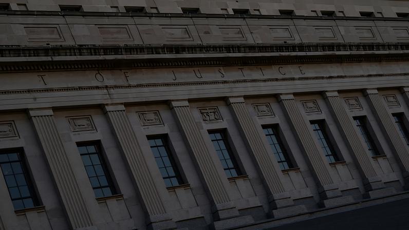 The exterior of the Department of Justice building with trees in the foreground.