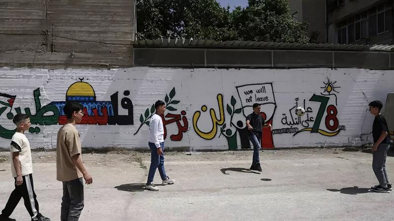 Jovens palestinos jogam futebol em Hebron, na Cisjordânia ocupada, ao lado de um mural em homenagem ao 78º aniversário da Nakba. (Imagem ilustrativa)