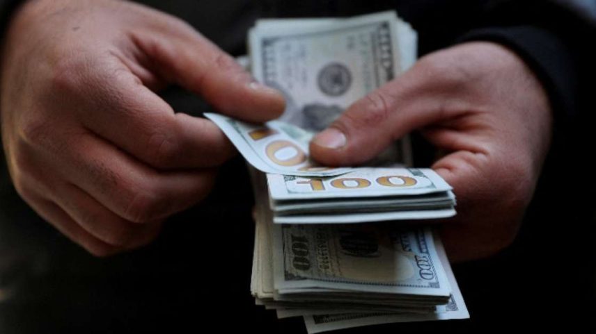 Homem conta notas de US$100 20 de dezembro de 2025 Majid Asgaripour/WANA (Agência de Notícias da Ásia Ocidental) via REUTERS