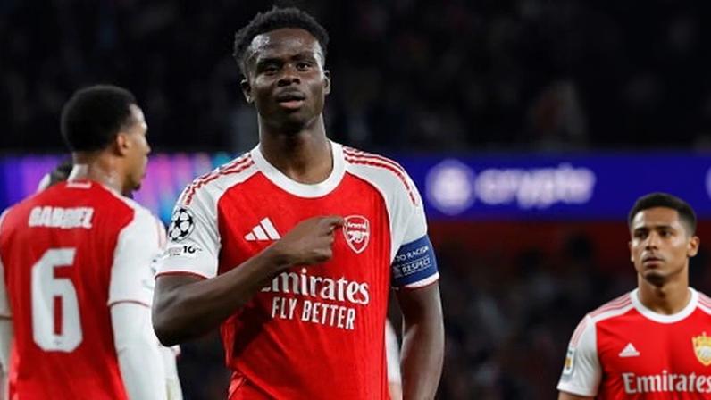 Bukayo Saka in a red and white Arsenal kit points to his chest in celebration after opening the scoring during Arsenal’s Champions League semi-final victory over Atletico Madrid