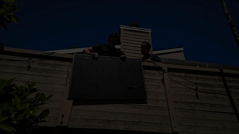 A man holds a solar panel on a balcony.