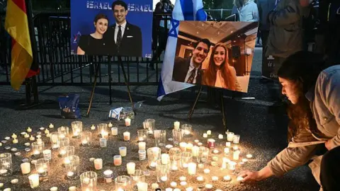 People attend a candlelight vigil for Yaron Lischinsky and Sarah Lynn Milgrim across from the White House in Washington, DC on 22 May 2025
