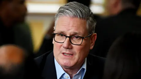 Getty Images Keir Starmer, in an open neck shirt and suit jacket, looking pensive