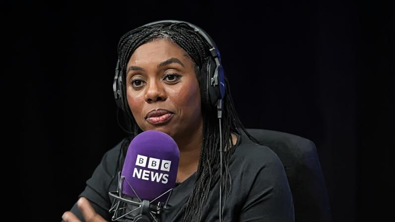 A woman sits in a purple radio studio