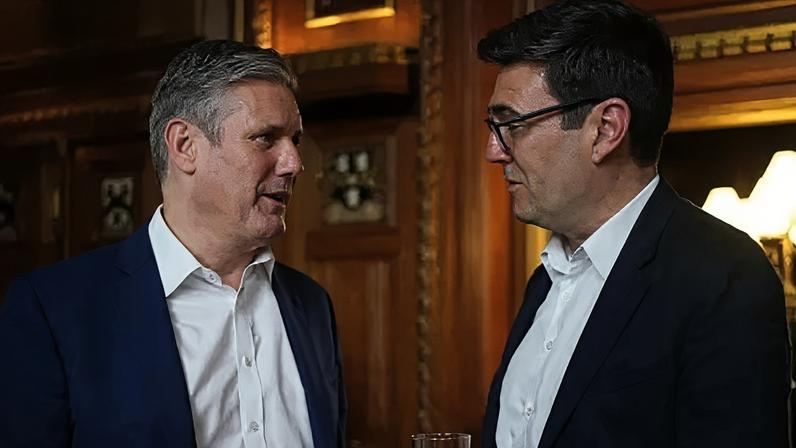 Sir Keir Starmer (left) and Andy Burnham talking. They are wearing white shirts and dark colour jackets. They are stood in a wood panelled room.