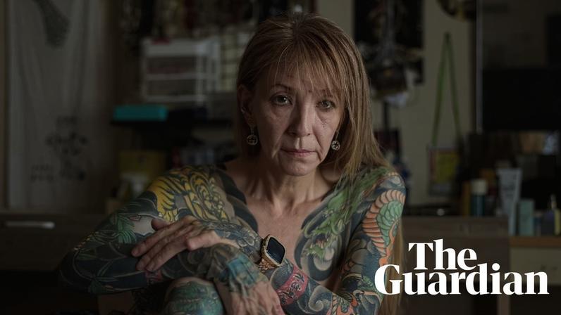 Nishimura, naked, sits on a bed showing her arms and legs covered in colourful tattoos. Nishimura, in Gifu, Japan, in 2025. Photograph: Shoko Takayasu/The Guardian