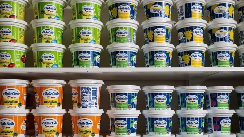 Rows of cancoillotte in different coloured pots on a shelf