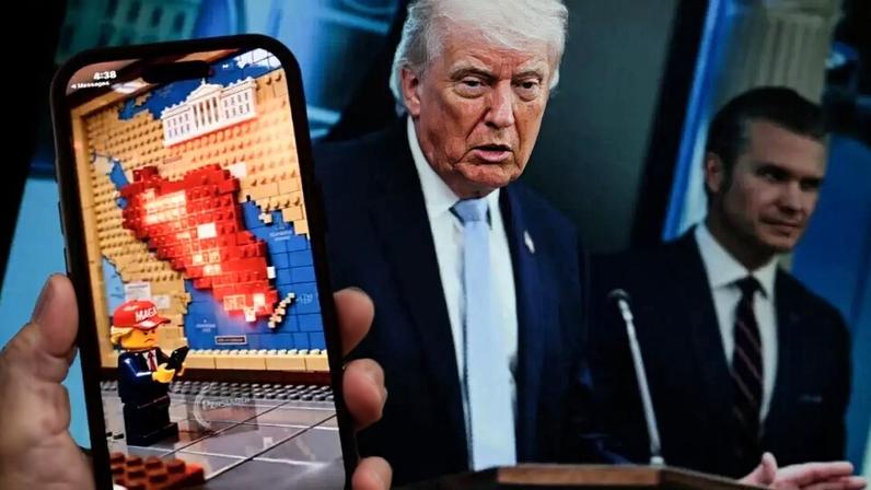 Esta foto ilustrativa, tirada em Los Angeles em 9 de abril de 2026, mostra um vídeo com temática de guerra, gerado por inteligência artificial e no estilo Lego, sendo reproduzido na tela de um smartphone em frente a uma foto do presidente dos EUA, Donald Trump, e do secretário de Defesa dos EUA, Pete Hegseth.
