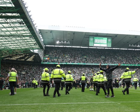 Police and stewards try to clear the pitch at Celtic Park.