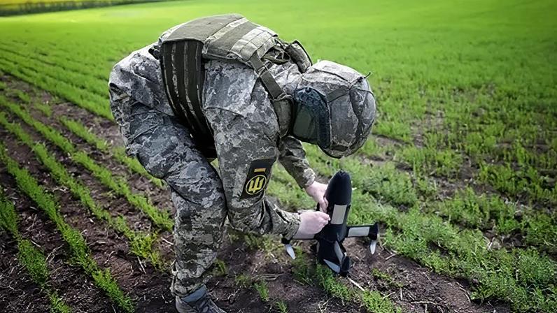 A Ukrainian soldier in uniform sets up an interceptor drone in a field
