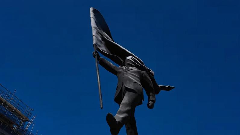 Uma estátua de um homem segurando uma bandeira cobrindo o rosto, e assinada 'Banksy', que apareceu em Waterloo Place, em Londres.