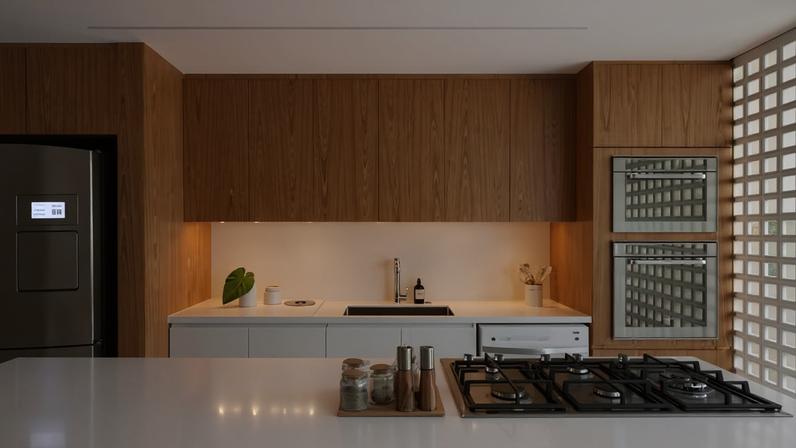 A marcenaria em lâmina natural de freijó Sayerlack e MDF branco agrega um toque sofisticação e aconchego ao espaço. Cooktop da marca Gorenje. Forno elétrico, micro-ondas e geladeira da Brastemp