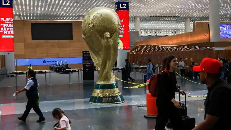 Passageiros passam por réplica gigante do troféu da Copa do Mundo no Aeroporto Internacional da Cidade do México 18 de maio de 2026 REUTERS/Henry Romero