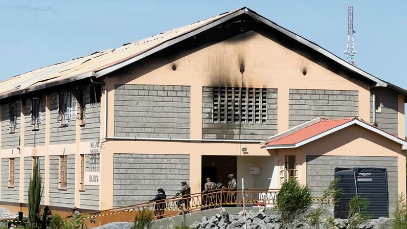 Security officers stand outside the fire-damaged dormitory at Utumishi girls academy in Gilgil.