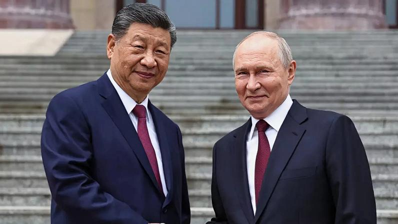 Xi Jinping e Vladimir Putin apertam as mãos em frente ao Palácio do Povo, em Pequim, a 20 de maio de 2026.