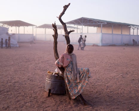 A Sudanese refugee girl fleeing from conflict rests next to a burnt tree in the middle of the Tine transit camp in Chad.