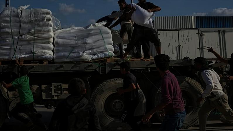 People grab sacks of flour from a moving lorry carrying World Food Programme aid in Gaza in November 2025.