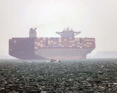 Iran-flagged container vessel Hamouna anchored as a small motorboat passes by, in the strait of Hormuz. Iran's Revolutionary Guards on 4 May denied that any commercial ships had crossed the strait after the US military earlier said two US-flagged merchant vessels had transited through the vital waterway as part of Project Freedom.