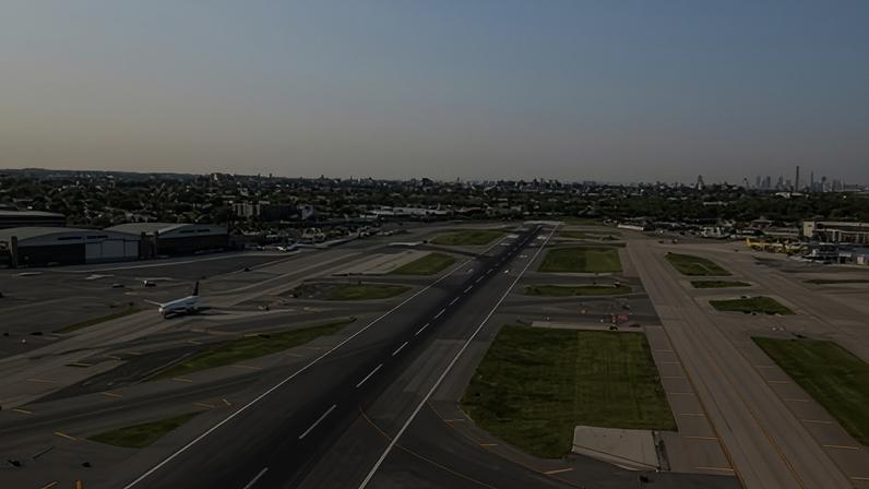 Aerial view of LaGuardia Airport runways and taxiways with green grass areas between them, and aircraft visible