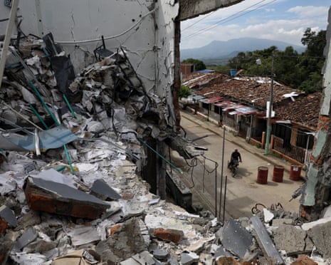 A man rides his motorcycle past the ruins of homes destroyed five months earlier in an attack by Farc dissidents in Cauca, Colombia.