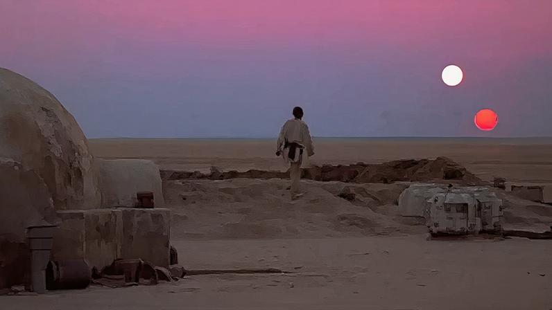 Luke Skywalker contempla um pôr-do-sol dobrado no planeta Tatooine, em uma cena clássica do primeiro filme Star Wars.