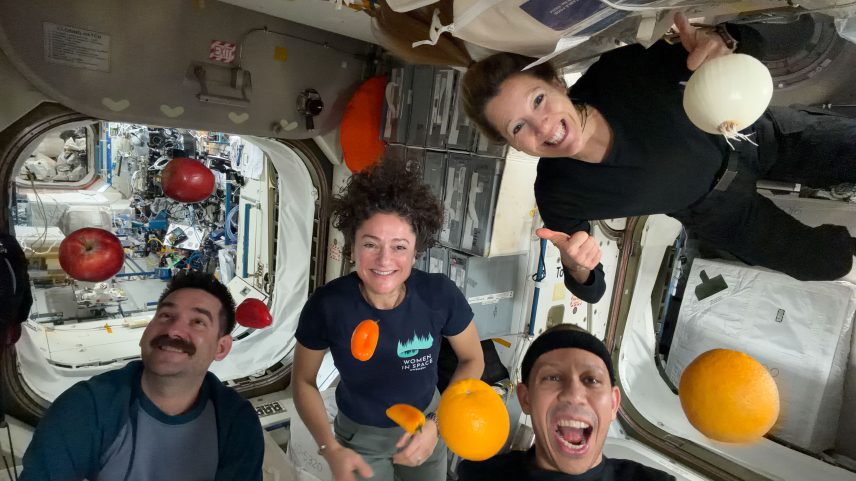 NASA astronauts Jack Hathaway (bottom left), Jessica Meir (middle left), and Chris Williams (bottom right), and ESA (European Space Agency) astronaut Sophie Adenot (top right) pose for a group photo aboard the International Space Station, as fruits and vegetables float around them.