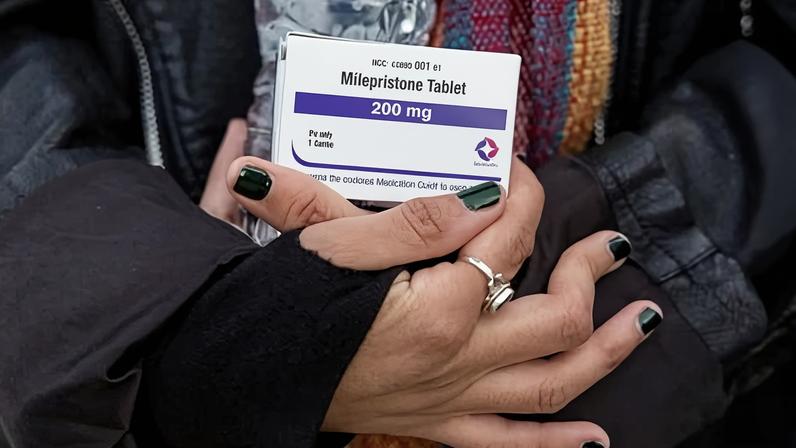 An abortion-rights activist holds a box of mifepristone pills.