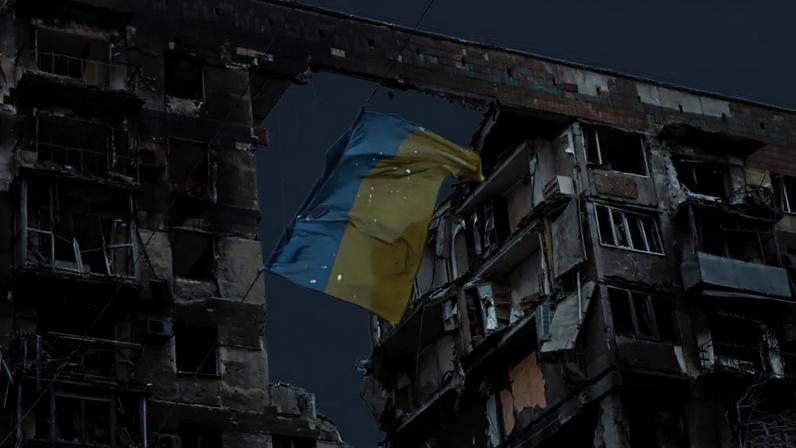 Em Mariupol, no leste da Ucrânia, uma bandeira ucraniana rasgada tremula diante de um prédio destruído. (Imagem ilustrativa)