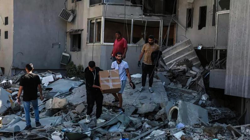 Moradores inspecionam os danos no local de um ataque israelense noturno na cidade de Tiro, no sul do Líbano, em 23 de maio de 2026.