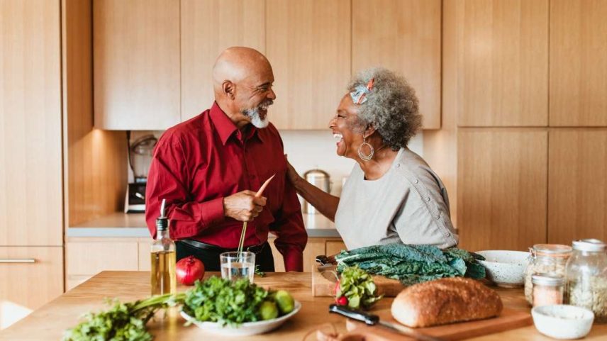 Casal de idosos negros preparando refeição em uma cozinha