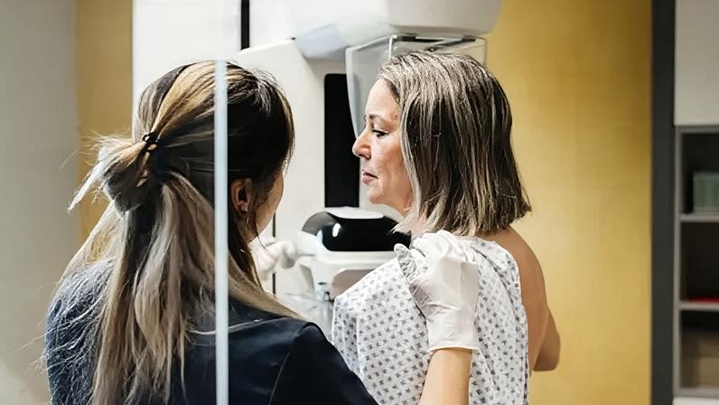 Getty Images A nurse provides assistance to a patient undergoing a mammogram in a modern medical facility.