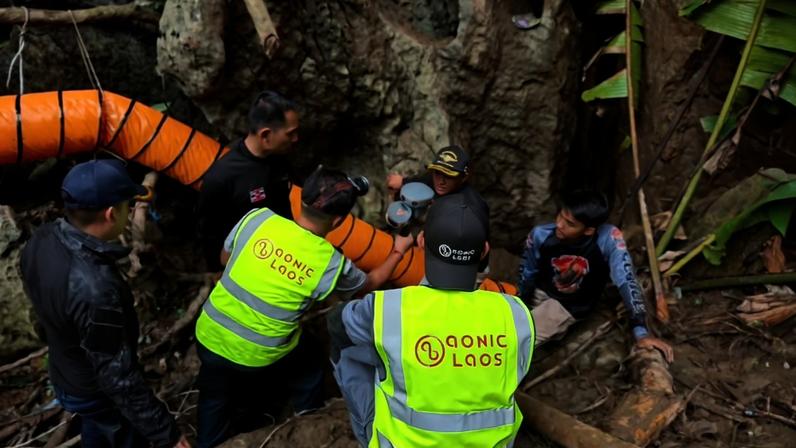 Imagem mostra mergulhadores se paramentando na frente da entrada de caverna para resgate