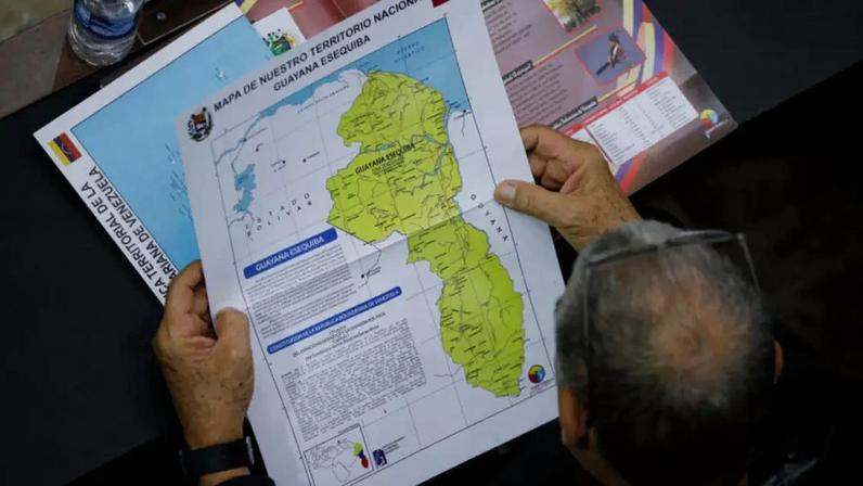Imagem de arquivo. Um membro da Assembleia Nacional da Venezuela segura um mapa que mostra a região disputada de Essequibo como parte do país em meio ao aumento das tensões entre Caracas e a Guiana, às vésperas de um referendo sobre o território, em 6 de dezembro de 2023.