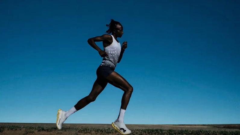 A runner running in On's new white lightspray sneaker model with a blue dusk sky in the backdrop.