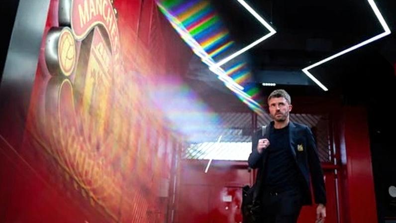 Michael Carrick walks by a Manchester United crest at Old Trafford