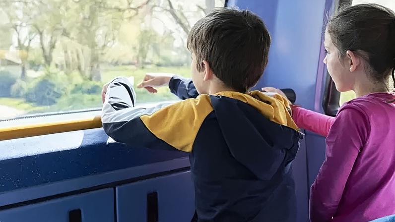 Getty Images A boy and a girl look out the front window on the top level of a bus