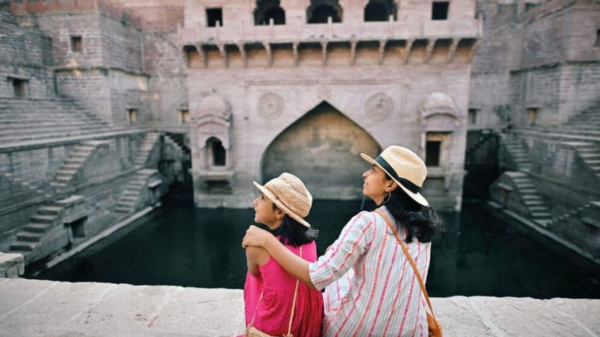 Rear view of tourist mother and daughter sitting at step well