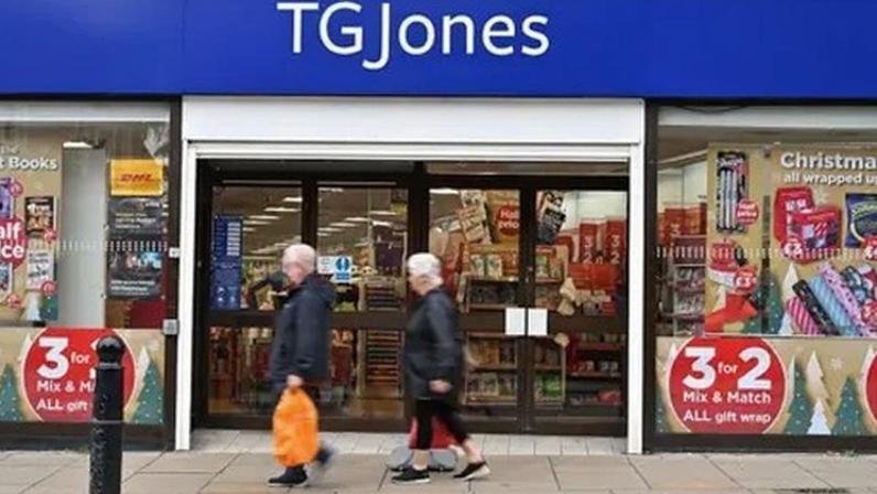 Getty Images A man and a woman walk past a doorway into a bookshop, with a blue banner sign above the door which says 'TG JONES'.