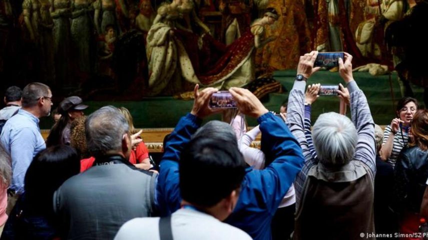 Visitantes observam obra com a coroação de Napoleão no Museu do Louvre, em Paris