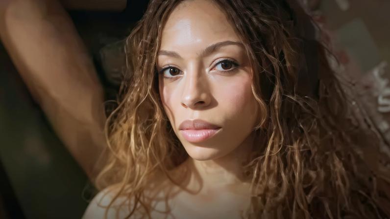 Spotify A mock up of the artist Ravyn Lenae's profile on Spotify with a green verified checkmark icon on her profile next to a picture of her staring at the camera with long curly hair. Underneath her picture it says "32.8m monthly listeners".